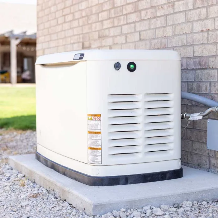 Standby home generator installed on a concrete pad beside a house